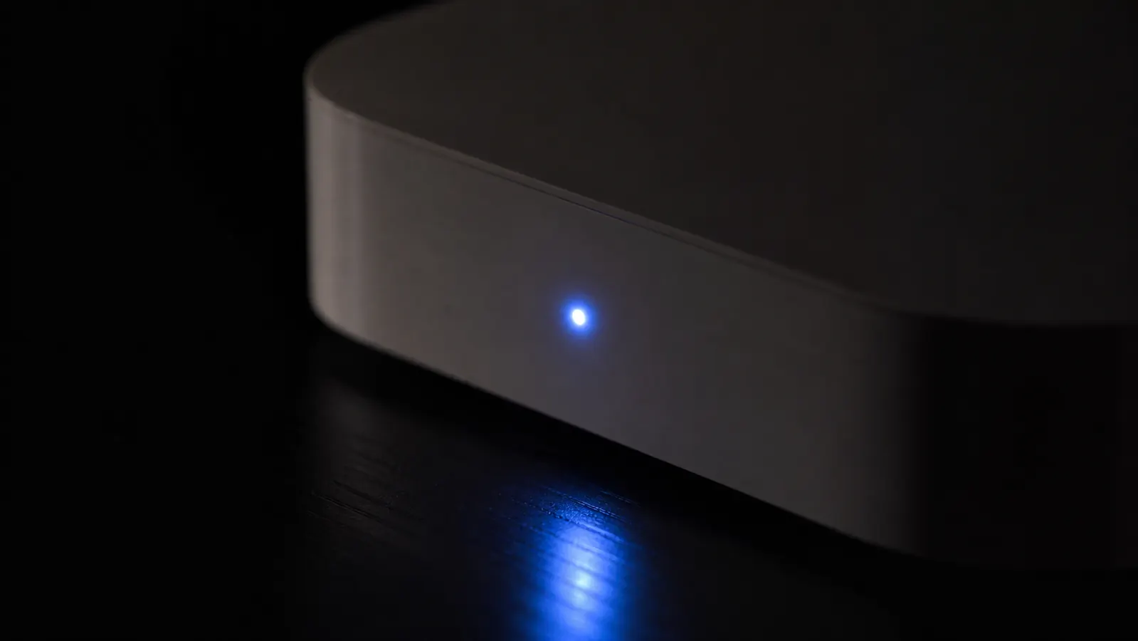 Small blue LED status light glowing on a white noise machine in a dark room